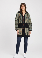 Model wearing the Green Camo Stripe Hooded Crochet Cardigan with dark jeans on a white studio background