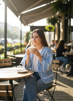 Model wearing the Sky Blue Granny-Stripe Crochet Cardigan at an outdoor cafe