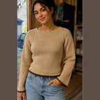 Camel-colored hand-knit boat-neck sweater with dark brown trim at the hem and flared cuffs.